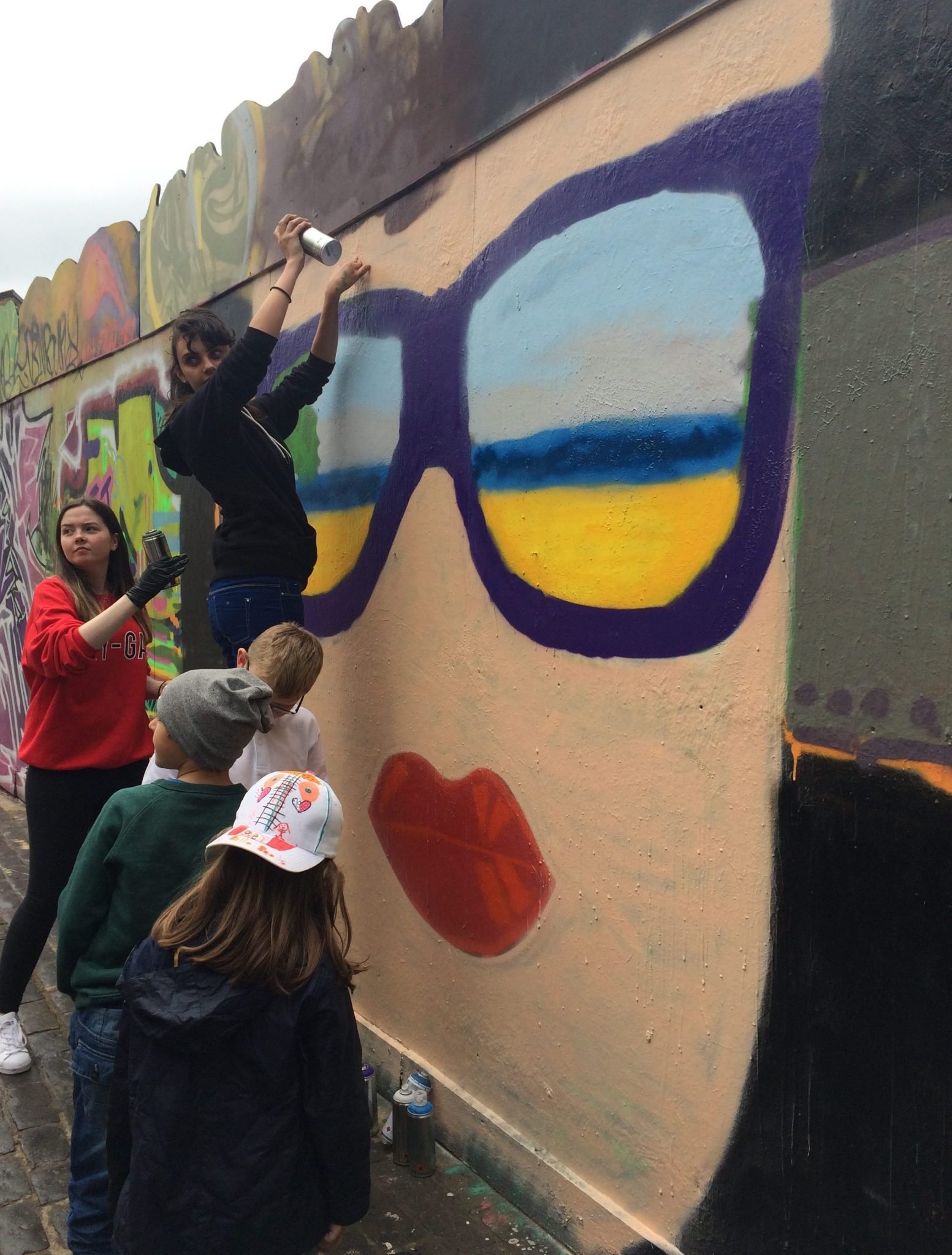 children stand in front of spray paint mural