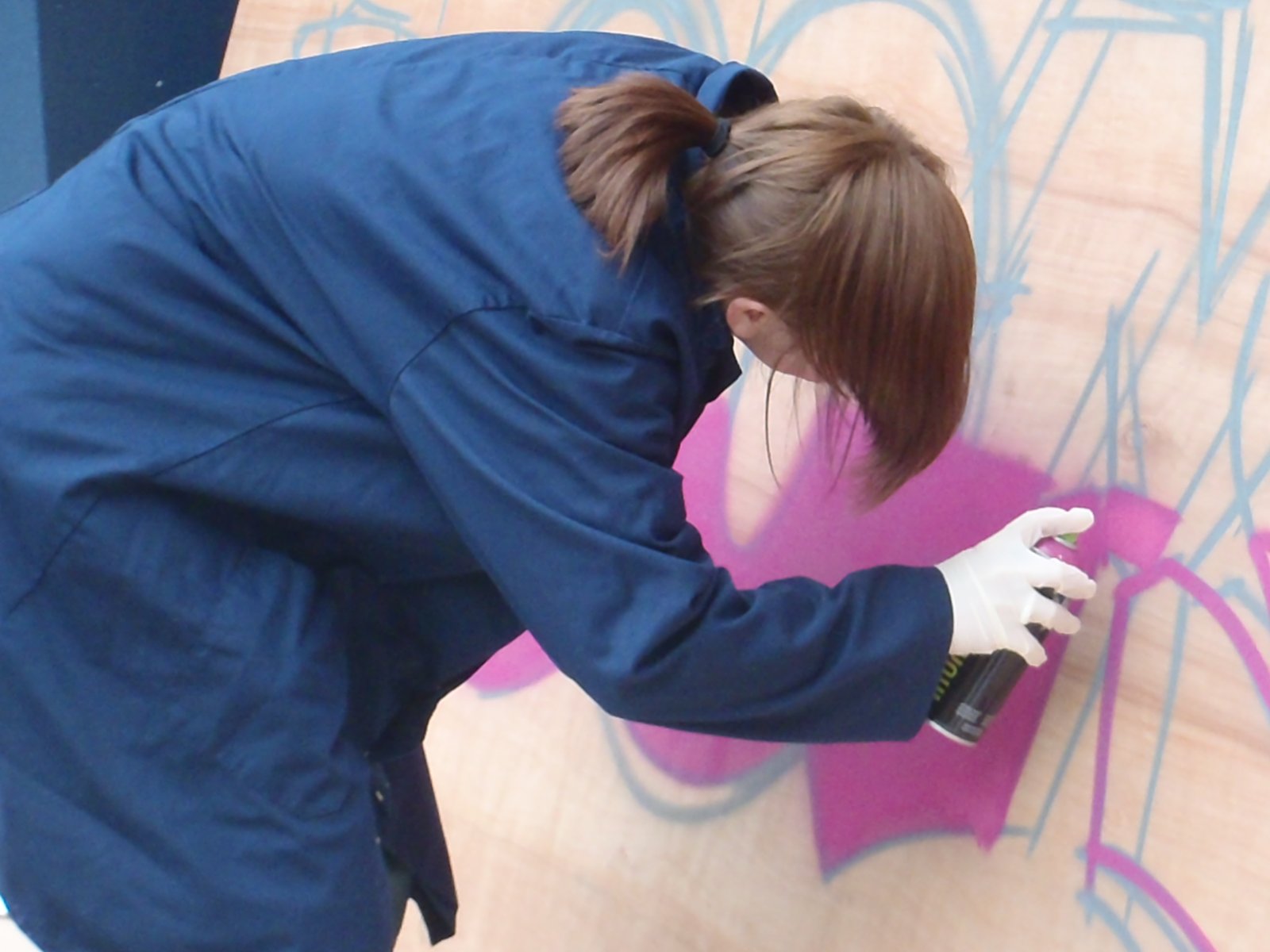 girl spray paints with purple paint at graffiti workshop in edinburgh