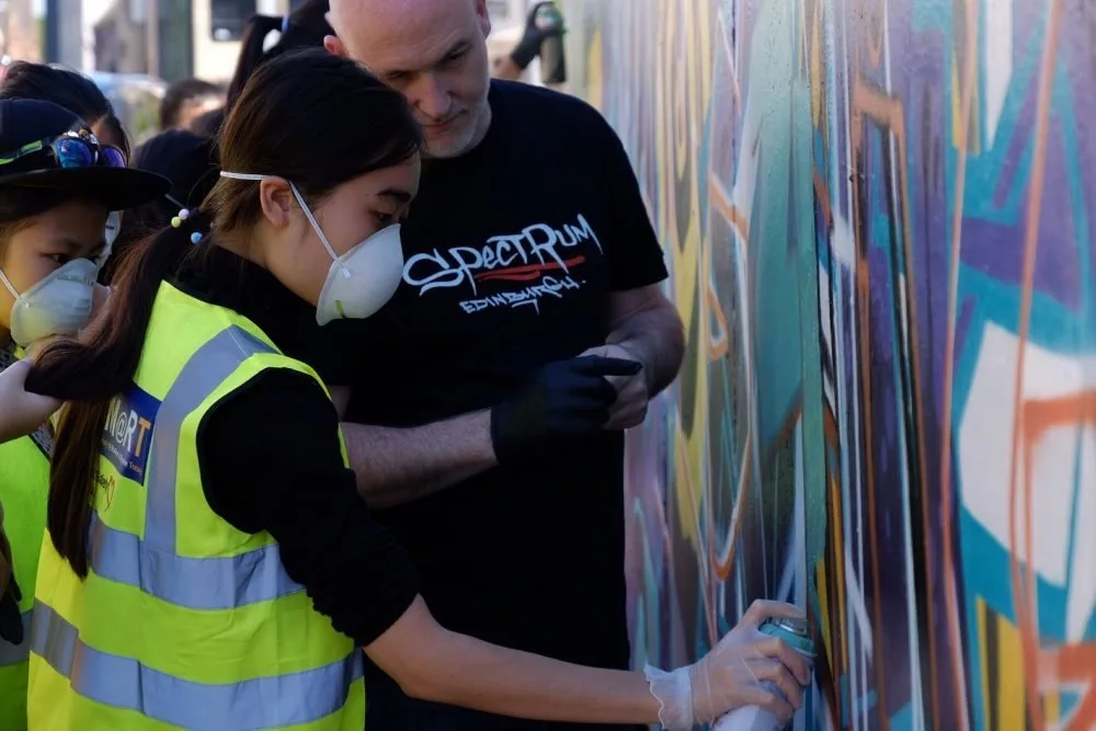 girl spray painting spectrum arts graffiti workshop